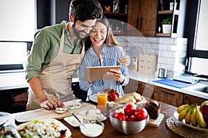 Copule in home kitchen looking at recipe on the web and cooking