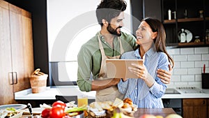 Copule in home kitchen looking at recipe on the web and cooking