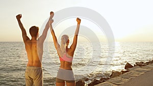 COPY SPACE: Athletic couple celebrates finishing workout near golden-lit beach