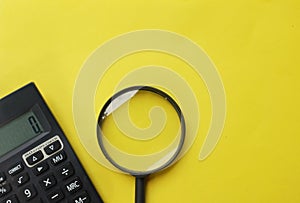 Copy space  black magnifying glass and calculator on yellow background.Business and finanse concept