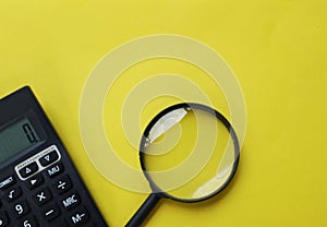 Copy space  black magnifying glass and calculator on yellow background.Business and finanse concept