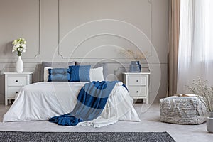 Copy space on empty grey wall of fashionable grey white and blue bedroom interior