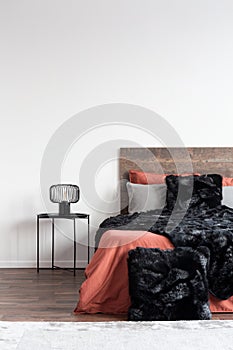 Copy space on empty white wall of simple bedroom interior with fury black duvet and pillow on bed