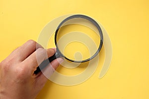 Copy space hand with a magnifying glass isolate on a yellow background.search symbol and And expanding clarity