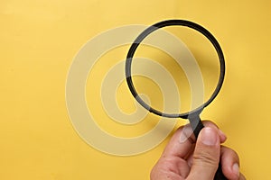 Copy space hand with a magnifying glass isolate on a yellow background.search symbol and And expanding clarity