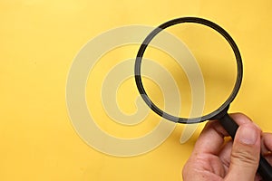 Copy space hand with a magnifying glass isolate on a yellow background.search symbol and And expanding clarity