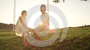 COPY SPACE LENSE FLARE Young boy and girl sitting on swing smiling at the camera