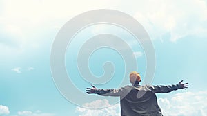 Copy space of man rising hands on blue sky white clouds abstract background. Freedom feel good and travel adventure concept