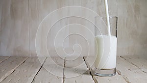 Copy space Pour yogurt into a glass on white vintage wooden boards. Milk drink in a transparent glass