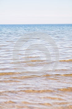 Copy space at the sea with a clear blue sky background above the horizon. Calm ocean waters at an empty beach. Peaceful