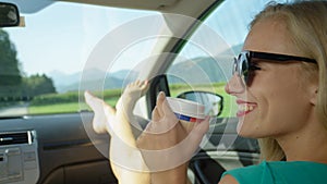 COPY SPACE: Smiling blonde woman drinks coffee while driving through countryside