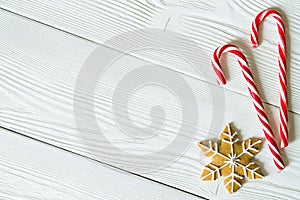 Copy space with sugar canes and Christmas gingerbread cookie in the shape of snowflake isolated on white wooden