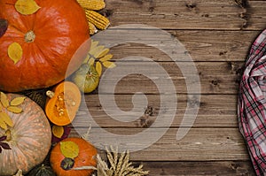 Copy space for Thanksgiving on a dark wooden background with a pumpkins, autumn leaves and a red checkered napkin