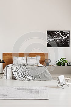 Copy space on white wall with black map in modern bedroom with king size bed with wooden headboard