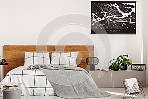 Copy space on white wall with black map in modern bedroom with king size bed with wooden headboard photo