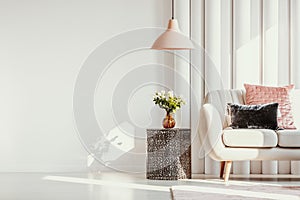 Copy space on white wall of elegant living room with white flowers on glass vase on stylish table next to white sofa photo