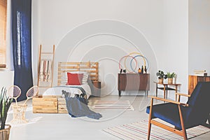 Copy space on the white wall of oldschool teenager bedroom with wooden furniture and dark blue accents