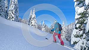 COPY SPACE: Woman splitboarding in Bohinj treks up hill covered in fresh snow.