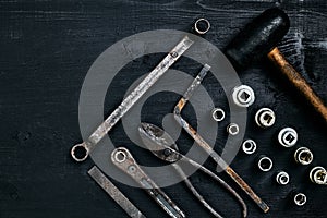Copy space of working tools on a black wooden surface. Nippers, wrench keys, pliers, screwdriver, hammer. Top view.