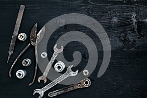 Copy space of working tools on a black wooden surface. Nippers, wrench keys, pliers, screwdriver. Top view.