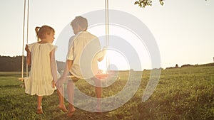 COPY SPACE: Young couple holding hands on swing at golden sunset