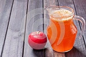 Copy spase photo of one red apple and fresh juice in the pitcher on table