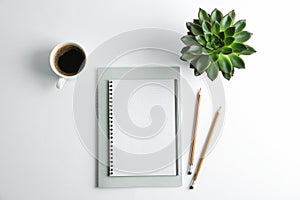 Copybooks, cup of coffee, pencils and succulent plant on white background