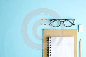 Copybooks, pencil and glasses on color background