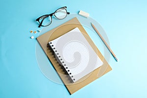 Copybooks, pencil and glasses on color background