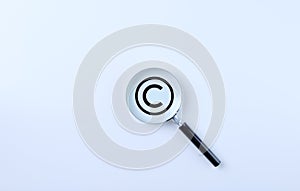 Copyright protection and patenting concept. Magnifying glass magnifies the copyright symbol on a white background. copyright