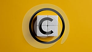 Copyright symbol on wooden blocks on yellow background. Concept of patenting or copyright protection