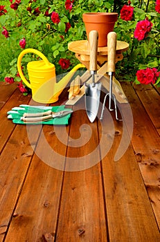 Copyspace gardening tools on wooden table and rose flowers background