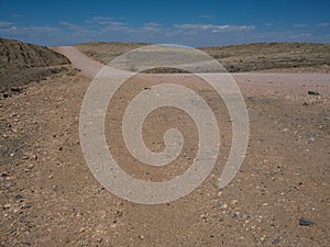 Copyspace of sandy road trip through dried dusty rock mountain landscape ground of Namib desert background with splitting stone a