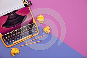 Copywriter. Vintage typewriter, crumpled paper balls and pencils on color background, top view. Space for text