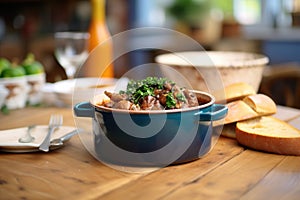 coq au vin in a ceramic pot on a wooden table, bread aside