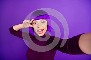Coquette lady making self photos sticking tongue out mouth showing v-sign wear trendy clothes  purple background