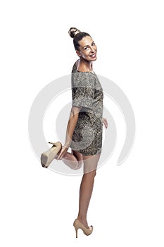 A coquettish beautiful woman in a short dress and high heeled shoes stands and smiles. Isolated on a white background. Vertical.