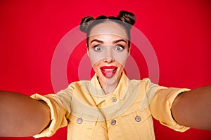Coquettish lady making selfies sticking tongue out of mouth casual stylish outfit isolated red background