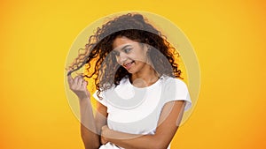 Coquettish smiling mixed-race woman twisting curls on finger, flirt gesture photo
