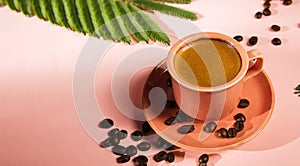 Coral colored cup with effuse coffee`s beans with shadows on pastel background. Minimalism, Coffee concept. Summer still life.