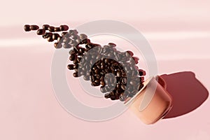 Coral colored cup with effuse coffee`s beans with shadows on pastel rose background. Flat lay. Top view. Coffee concept. Pop art