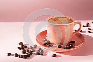 Coral colored cup with effuse coffee`s beans with shadows on pastel rose background. Flat lay. Top view. Coffee concept. Pop art