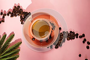 Coral colored cup with effuse coffee`s beans with shadows on pastel rose background. Flat lay. Top view. Coffee concept. Summer