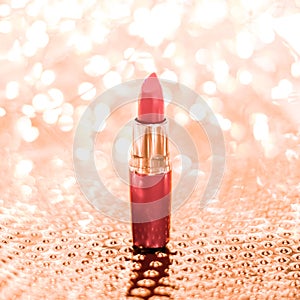 Coral lipstick on rose gold Christmas, New Years and Valentines Day holiday glitter background, make-up and cosmetics product for