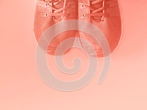 Coral pink trainers on empty background.