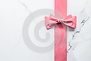 Coral silk ribbon and bow on marble background, girl baby shower present and glamour fashion gift decor for luxury beauty brand,