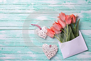 Coral tulips in white envelope and two white decorative hearts