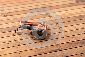 a corded nailer with a metal clip on a wooden floor