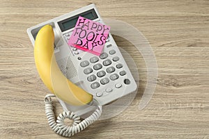 Corded phone with banana as handset and words Happy Fool`s Day on wooden table, above view. Space for text