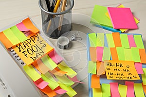 Corded phone and notebook covered with sticky notes on wooden table. April fool`s day celebration